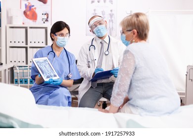 Specialist doctor and nurse presenting diagnosis to senior woman on tablet pc in time of covid19 pandemic. Medical physician specialist during coronavirus outbreak discussing with patient