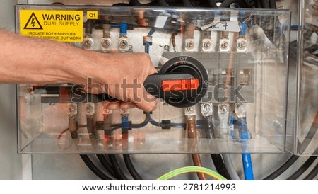 Specialist electrical test and commissioning engineer activating a power breaker on an automatic transfer switch. Emergency systen back up generator for electrical power.