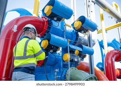 A specialist engineer is inspecting the structural integrity of the water tank and high-pressure pipes.