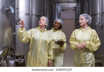Specialist engineer technicians staff protective clothing smile talk hand holding tablet inspect check quality control work job wine vats barrels on modern technology factory industry plant warehose