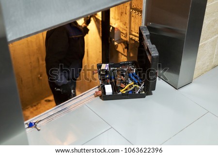 Specialist fixing or adjusting lift mechanism in elevator schaft. Regular repair, service and maintenance of elevator