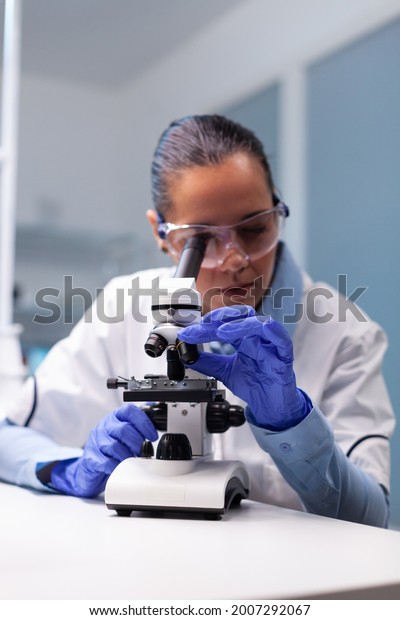 Specialist pharmacist examining bacteriology\
infection lab test using medical microscope working in pharmacology\
hospital laboratory. Scientist microbiologist analyzing\
microbiology\
expertise