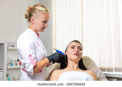 Specialist Pierces The Client's Ears With A Piercing Gun. Caucasian Woman Having Ear Piercing Process. Beauty Procedure At A Salon.