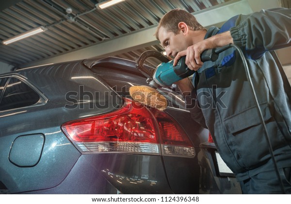 Specialist\
polishes car headlights with a round\
brush