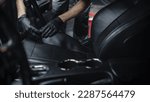 Specialist Professional Car Cleaning and Detailing Company Vacuum Cleaning an Ecological Perforated Black Faux Leather Interior in a Modern Sportscar. Worker Cleaning Every Little Seam on the Car Seat