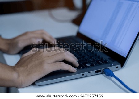 specialist programmer man hand type configuration code on at laptop for check software function for fix bug and defect of security system in dark datacenter room for engineering and technology concept
