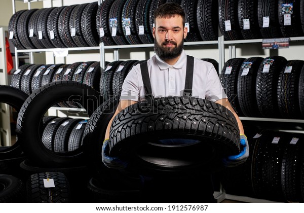 specialist tire fitting in car service, auto\
mechanic checks tire and rubber tread for safety, concept: repair\
of machines, fault diagnosis, repair specialist, technical\
maintenance. car service\
shop
