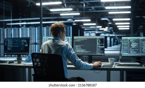 IT Specialist Uses Computer in Data Center. Server Farm Cloud Computing Facility with Male Maintenance Administrator Working During the Evening. Cyber Security and Network Protection. - Shutterstock ID 2136788187