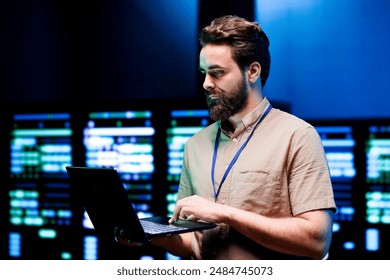 Specialist using laptop to do scans on blade servers in data storage facility. Cloud computing computer service business used for complex calculations and massive datasets processing - Powered by Shutterstock