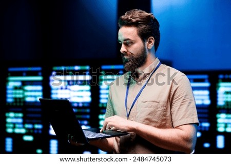 Specialist using laptop to do scans on blade servers in data storage facility. Cloud computing computer service business used for complex calculations and massive datasets processing