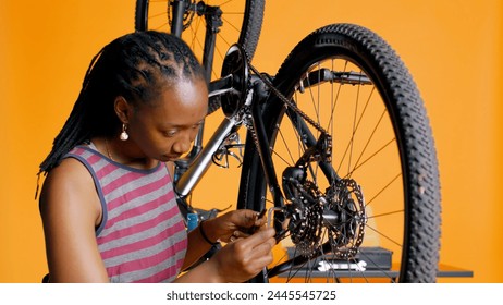 Specialist using screwdriver and hex socket wrench to secure wheel on bicycle in studio background repair shop. Technician screwing bolts on bike parts, fixing rear derailleur, camera B - Powered by Shutterstock