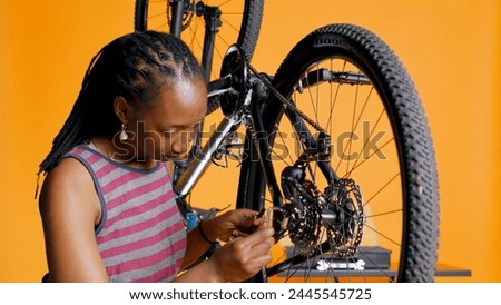 Specialist using screwdriver and hex socket wrench to secure wheel on bicycle in studio background repair shop. Technician screwing bolts on bike parts, fixing rear derailleur, camera B