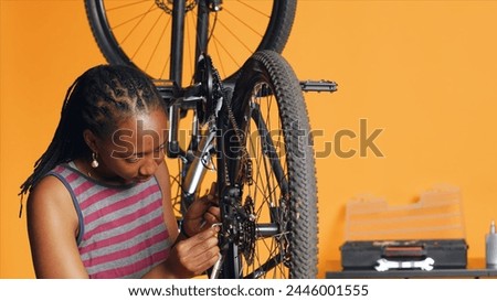 Specialist using screwdriver and hex socket wrench to secure wheel on bicycle in studio background repair shop. Technician screwing bolts on bike parts, fixing rear derailleur, camera A