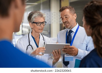 Specialist and woman doctor having a discussion in hospital hallway about new therapy. Senior doctor discussing patient case status with his medical staff after operation. Doctor in conversation. - Powered by Shutterstock