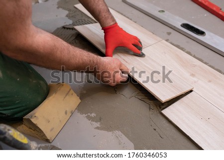 A specialized construction worker sticks a ceramic tile in the bathroom room.