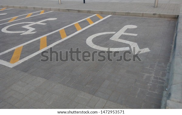 specialized handicapped parking lot in front\
of mosque with handicapped symbol with white paint and yellow\
paints applied on tarmac road or asphalt\
road