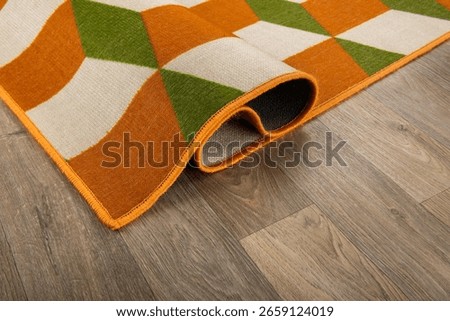 A specially designed carpet is folded on a wooden floor.