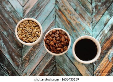 Specialty coffee concept. Green raw coffee beans, roasted coffee beans and black coffee in three white cups on turquoise wooden parquet background top view - Shutterstock ID 1656435139