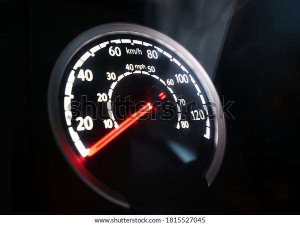 Specific speedometer on\
dark background. It comes from HGV truck dashboard, blurred, miles\
and kilometers