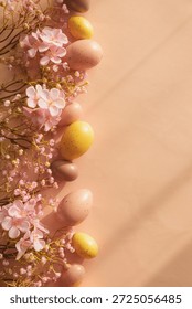 Speckled Easter Eggs and Cherry Blossoms on Peach Background. Festive Spring Flatlay