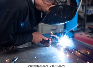 Spectacular conceptual image of a blacksmith busy using the welding machine. Sparks and smoke flash from the tip of the soldering iron. Blurred background. Welding, repair, work concept. Copy space. - Powered by Shutterstock