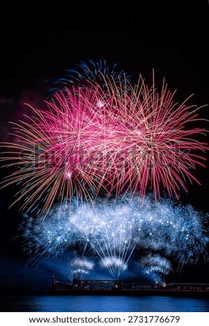 A spectacular fireworks display exploding in vibrant colors against a deep black night sky. Bursts of red, pink, blue, and gold light radiate outward, on Atlantic festival. Funchal, MAdeira island, Portugal