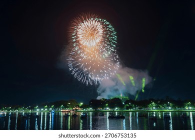 Spectacular gold fireworks exploding over the Perfume River in Hue, reflecting on the dark water amidst boats and green lasers.