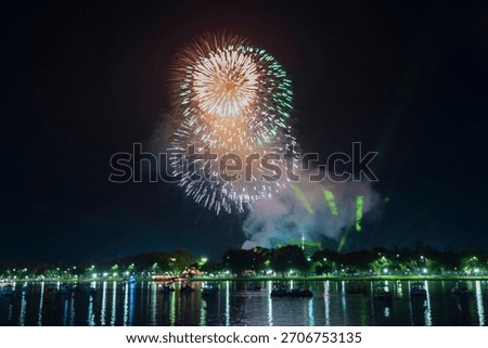 Spectacular gold fireworks exploding over the Perfume River in Hue, reflecting on the dark water amidst boats and green lasers.