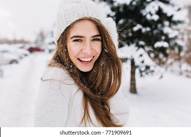 Spectacular Long-haired Woman Laughing While Posing On Snow Background. Outdoor Close-up Photo Of Caucasian Female Model With Romantic Smile Chilling In Park In Winter Day.