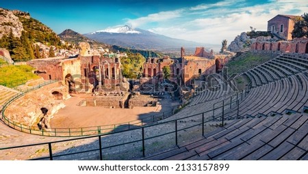 Spectacular morning view of Taormina town and Etna volcano on background. Sunny summer scene of ancient Greco-Roman theater, Sicily, Itale, Europe. Traveling concept background.