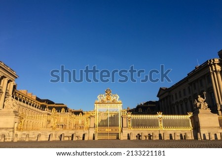 The spectacular Palace of Versailles in France in the early morning sunlight: the golden Gate of Honour in front of the Royal Courtyard