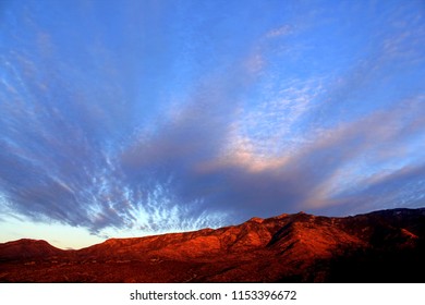 Spectacular Pastel Pink Purple Orange Monsoon Sunset Clouds  Over The Glowing Red  Pusch Ridge Santa Catalina Mountains In The Tucson Arizona Desert