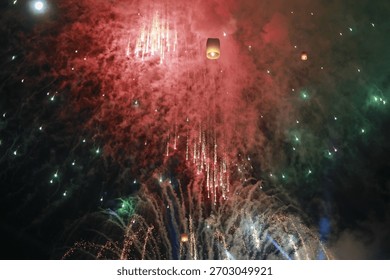 Spectacular red firework exploding in dark night sky. glowing sky lantern floats during joyful festival celebration with beautiful pyrotechnic show, dazzling event