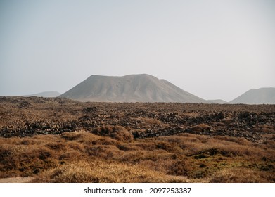 Spectacular scenery of Calderon Hondo volcano with rocky surface located in dry valley under cloudless sky on Fuerteventura island