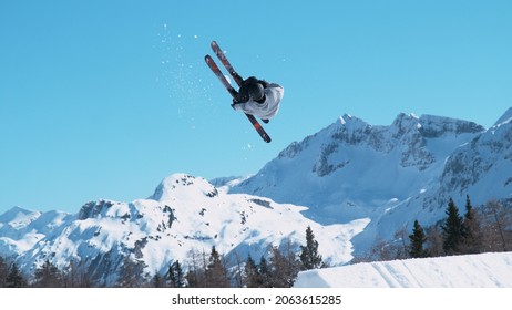 Spectacular shot of an extreme skier jumping off a kicker and doing a beautiful backflip. Athletic male tourist freestyle skiing in the Japanese mountains does a flip trick on a sunny winter day. - Powered by Shutterstock