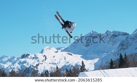 Spectacular shot of an extreme skier jumping off a kicker and doing a beautiful backflip. Athletic male tourist freestyle skiing in the Japanese mountains does a flip trick on a sunny winter day.