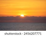 Spectacular sunrise on the horizon with the sea at your feet. Romantic sunrise. Beach sunrises. The sun tries to rise through the clouds in the orange sunrise.