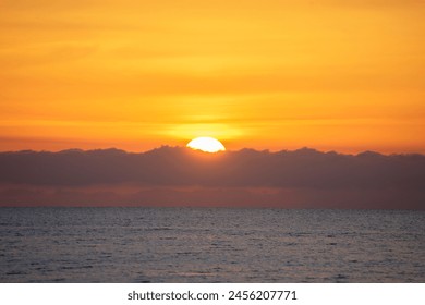 Spectacular sunrise on the horizon with the sea at your feet. Romantic sunrise. Beach sunrises. The sun tries to rise through the clouds in the orange sunrise.