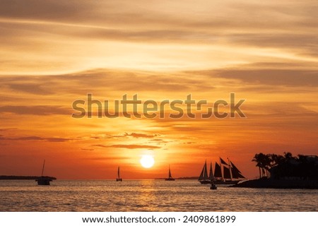A spectacular sunset, off the coast of Key West, Florida, with sailing boats silhoutted against the orange sky
