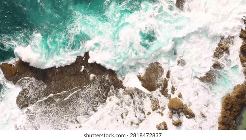 A spectacular top-down drone view capturing crystal-clear sea waves crashing onto a pristine sandy beach. The mesmerizing patterns of white surf meeting the golden shoreline create a striking coastal landscape, perfect for travel, summer, vacation, marine nature, and aerial photography concepts.