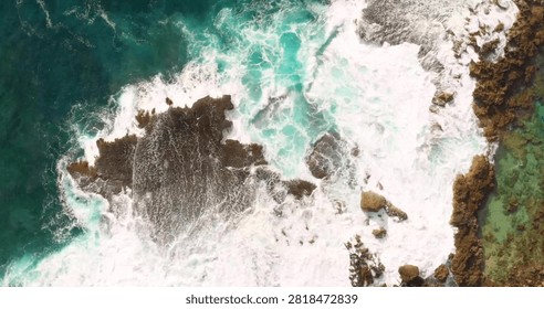 A spectacular top-down drone view capturing crystal-clear sea waves crashing onto a pristine sandy beach. The mesmerizing patterns of white surf meeting the golden shoreline create a striking coastal landscape, perfect for travel, summer, vacation, marine nature, and aerial photography concepts.