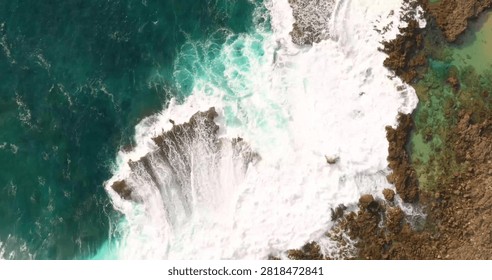 A spectacular top-down drone view capturing crystal-clear sea waves crashing onto a pristine sandy beach. The mesmerizing patterns of white surf meeting the golden shoreline create a striking coastal landscape, perfect for travel, summer, vacation, marine nature, and aerial photography concepts.