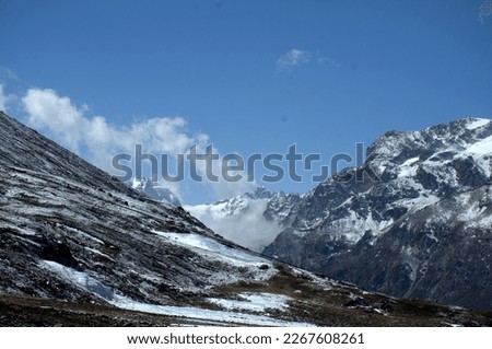 Spectacular view of small stone stacks scattered around the scenic zero point North Sikkim. Snowy mountain range towers above base camp in the breathtaking Himalayas. View of windswept Himalayan Range