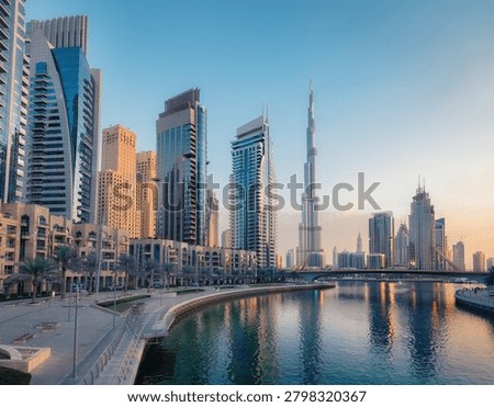 A spectacular wide-angle cityscape capturing the hyper-modern, soaring glass skyscrapers of downtown Dubai, United Arab Emirates. The image showcases sleek, ultra-tall corporate towers, architectural marvels, and luxury high-rise residences flanking a pristine, multi-lane urban boulevard. Bathed in the warm, golden light of a desert sunset, the brilliant glass facades reflect the glowing horizon, while manicured palms line the pathways below. This cutting-edge urban center represents ultimate luxury and engineering ambition, making it an exceptional asset for global wealth management brochures, luxury real estate marketing, international travel banners, and modern Middle Eastern lifestyle editorials.