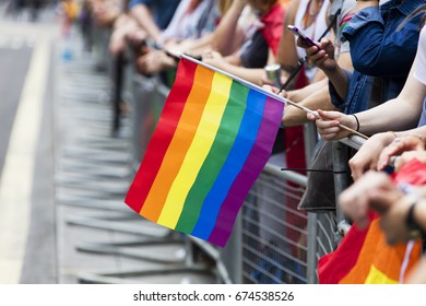 A Spectator Waves A Gay Rainbow Flag At An LGBT Gay Pride March In London