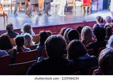 Spectators At A Theater Performance, In A Cinema Or At A Concert. Shooting From Behind. The Audience In The Hall. Silhouettes Of People.