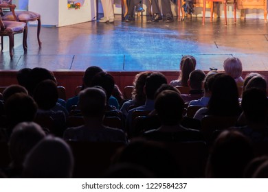 Spectators At A Theater Performance, In A Cinema Or At A Concert. Shooting From Behind. The Audience In The Hall. Silhouettes Of People.