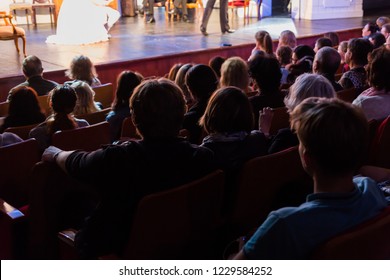 Spectators At A Theater Performance, In A Cinema Or At A Concert. Shooting From Behind. The Audience In The Hall. Silhouettes Of People.