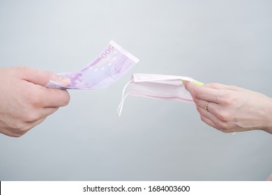 Speculation About Medical Masks. People Sell Masks Very Expensive, Because There Are Not Enough Of Them. Hands Pass The Mask And Money To Each Other. Plain White Studio Background.