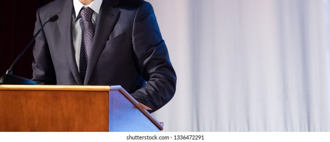 Speech of an abstract man in a suit on stage at the stand for performances. Tribune or pulpit for speaker official, president or professor. Close-up. Copy space. - Shutterstock ID 1336472291